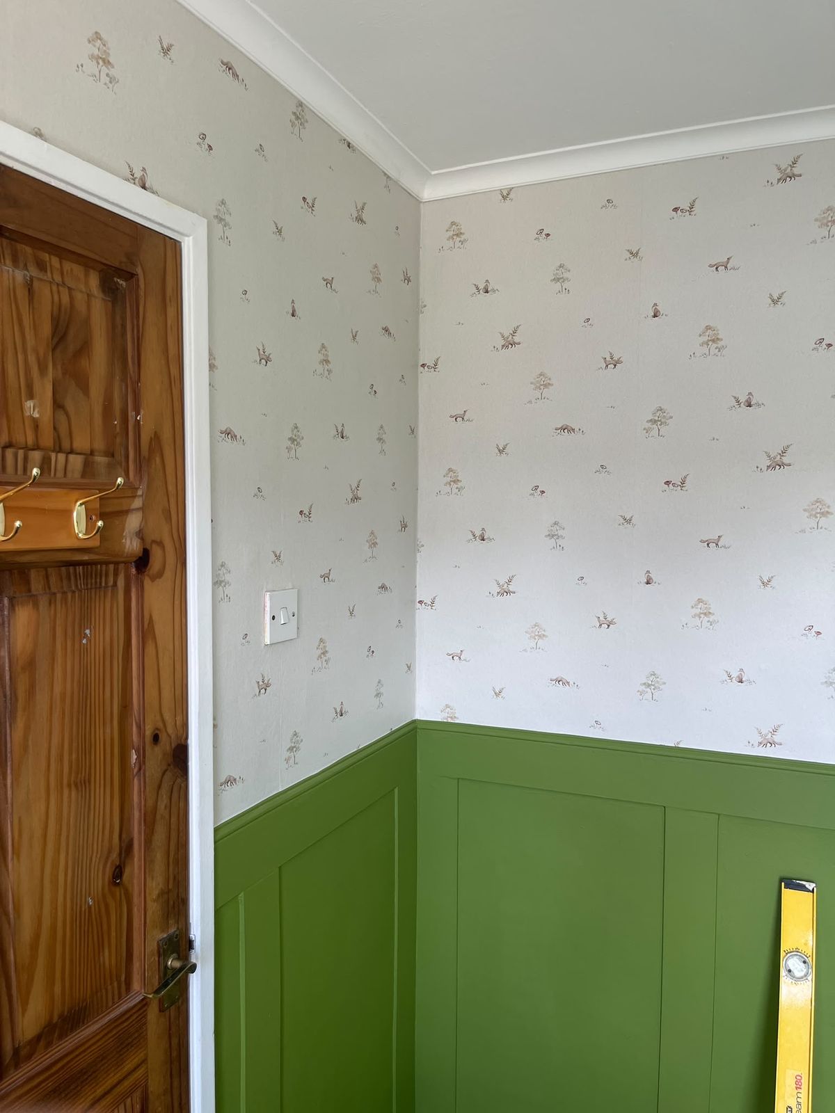 Woodland animal print wallpaper above green painted panelling in a Chelmsford home